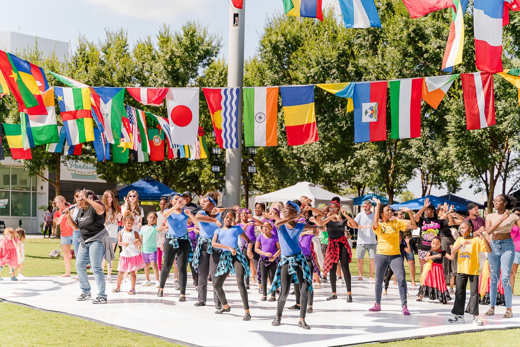 Dancers performing outdoors beneath international flags